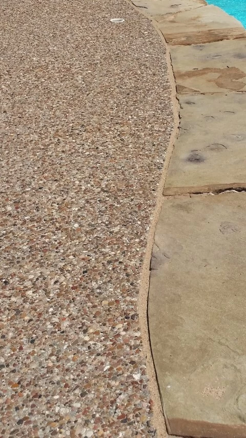 tan pool mastic with sand next to pebble deck and light brown rock coping
